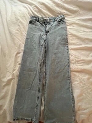 Ljusblå wide jeans med rå kant - Snygga ljusblå jeans med breda ben och rå, ofållad kant nertill. Klassisk femficksmodell i denim med hög midja och raka sömmar. Perfekta för en avslappnad och trendig look.