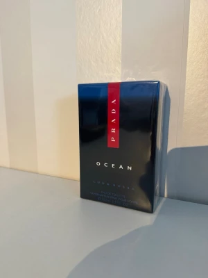 Prada Luna Rossa Ocean EdT 100ml - Prada Luna Rossa Ocean Eau de Toilette är en maskulin parfym i en elegant mörkblå förpackning med röd detalj och vit text. Flaskan rymmer 100 ml och doften är inspirerad av havet, vilket ger en fräsch och modern känsla.