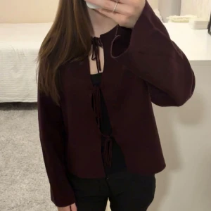 Vinröd kofta med knytband - Vinröd kofta från Gina Tricot med knytband framtill. Modellen är croppad och har långa ärmar. Perfekt att styla över ett linne eller t-shirt.