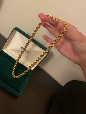 Guldfärgat repkedje-halsband Aimieci - Snyggt halsband från Aimieci i guldfärgad metall med repkedje-design. Kedjan har en tvinnad form som ger ett exklusivt intryck och kommer i en grön sammetsask. Perfekt accessoar för att lyfta din outfit.