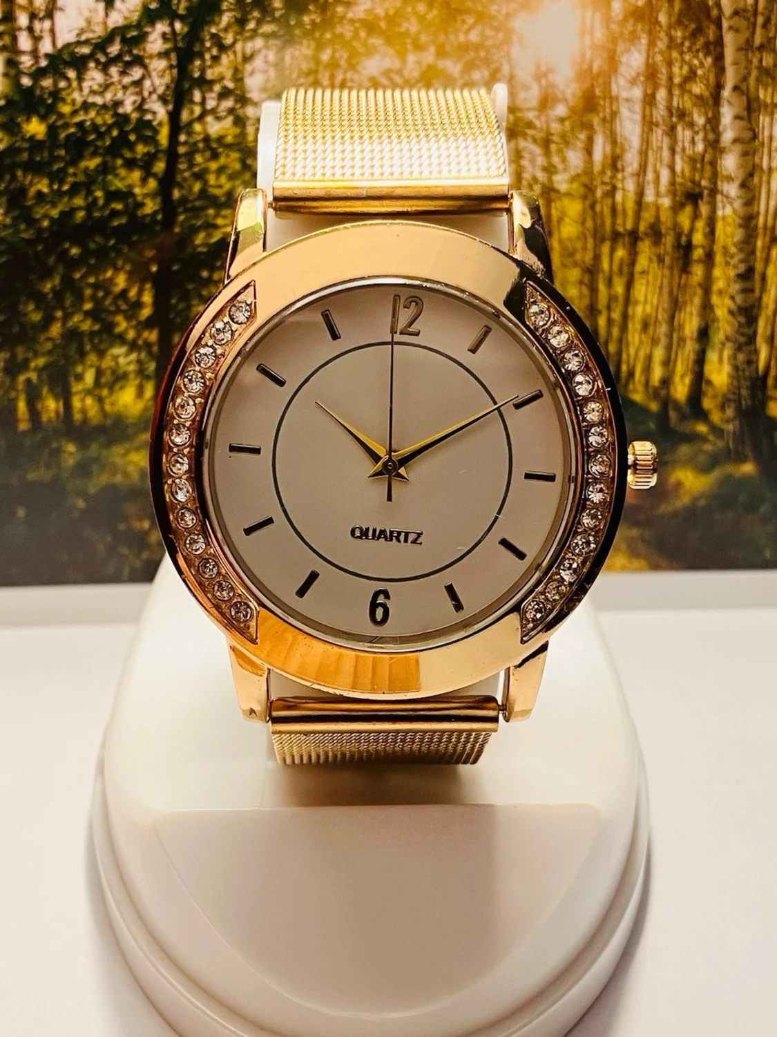 Guldig klocka med mesharmband och stenar