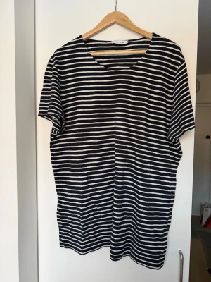 Randig t-shirt från Samsøe Samsøe - Snygg randig t-shirt från Samsøe Samsøe i marinblått och vitt. Klassisk passform med rund hals och korta ärmar. Perfekt till jeans eller shorts för en avslappnad stil.