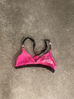 Rosa bikini överdel, barnstolek!! 7-8y  - Sportig rosa bikini topp  från Wato med svarta justerbara axelband och svart resår under bysten. Bikinin har en enkel, mjuk design utan bygel och tryckt logga på ena sidan. 