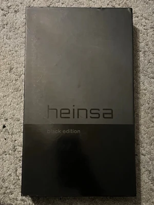 Heinsa Black Edition pingisracket - Säljer ett 5 sjärnigt Heinsa Black Edition pingisracket i svart med två vita pingisbollar. Racket har en stilren design och är märkt med 'Gambler Zero'. Perfekt för dig som vill ha en snygg och unik utrustning till bordtennisen.