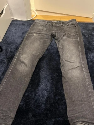 Mörkgrå jeans från Replay - Snygga mörkgrå replay jeans med klassisk femficksdesign och raka ben. Jeansen har en diskret slitning vid ena fickan och är tillverkade i mjukt bomullsjeansmaterial. Perfekta för dig som gillar en tidlös och clean look.