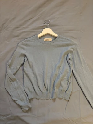 Ljusblå stickad tröja Pull&Bear - Snygg ljusblå stickad tröja från Pull&Bear med rund halsringning och långa ärmar. Tröjan har ribbade muddar vid ärmslut och nederkant, vilket ger en klassisk och stilren look. Perfekt att matcha med jeans eller kjol.