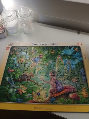 Sagopussel med älvor Ravensburger - Fint pussel med 40 bitar från Ravensburger med sagotema. Motivet visar älvor, fjärilar och magiska växter i en färgglad skogsmiljö. Passar för barn från 4 år och uppåt. Pusslet har en stadig ram i gul kartong. (Kommer inte i orginalkartong)