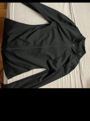 Black sport jacket - Stilren svart vindjacka med hel dragkedja framtill och långärmad design. Jackan har en minimalistisk look och är tillverkad i ett lätt syntetmaterial som passar perfekt för blåsiga dagar. Enkel att matcha med olika outfits och perfekt för dig som gillar en clean stil.