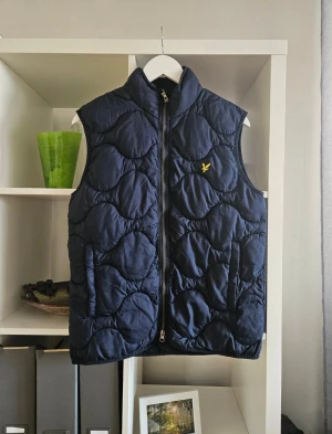 Lyle & Scott, mörkblå väst - Storlek XS men passar även en S. Använd några fåtal gånger men finns inga defekter. Längd 65 cm och från armhåla till armhåla 50 centimeter.