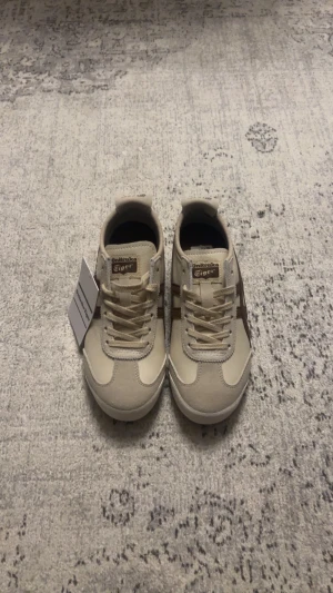 Onitsuka Tiger skor - Snygga beige sneakers från Onitsuka Tiger med bruna detaljer och klassisk logga på tungan och hälen😊