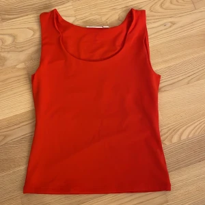 Röd linnetopp från Kappahl XS - Snygg röd linnetopp från Kappahl i storlek XS. Toppen har en rundad halsringning och är ärmlös, perfekt för varma dagar. Materialet är mjukt och stretchigt, vilket gör den bekväm och enkel att styla med dina favoritjeans eller kjol.