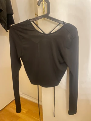 Croppad, öppen i ryggen top - Croppad, långärmad top som man knyter i ryggen köpt från Nelly för ett par år sen. Kom inte till användning. Storlek S eller M (minns inte😅).