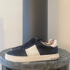 Valentino flycrews marinblå - Säljer ett par snygga Valentino Garavani sneakers i marinblått läder Perfekt för dig som gillar stilrena och lyxiga detaljer. Made in Italy.