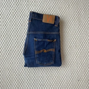 Mörkblåa Nudie jeans - Mörkblåa tape ted jeans i storlek 28/30 (97,5x34cm) som är lagade vid grenen men syns ej! Färgen på bilden är konstig men se bild 6! Nypris är 1600! Skriv vid frågor eller funderingar!