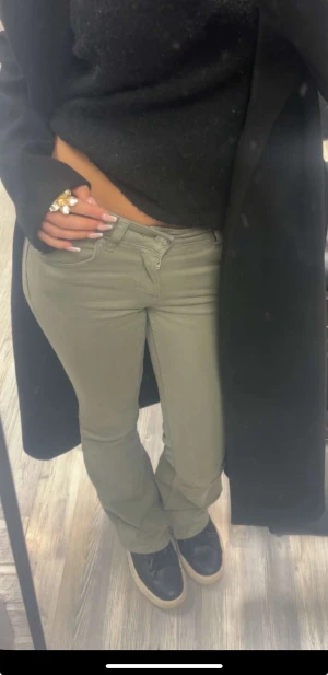 Olivgröna bootcut byxor - Snygga olivgröna byxor med bootcut-snitt och klassisk femficksdesign. De har låg midja. Använd 1 gång. Säljer pga att de it kommer till användning