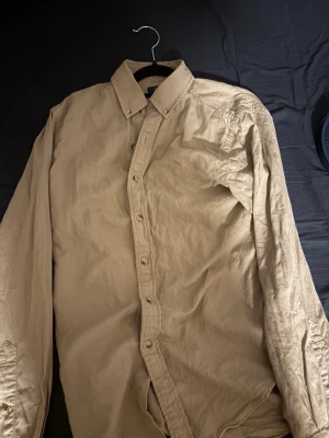 Beige Ralph Lauren skjorta - Säljer en polo skjorta i nästan ny skick, perfekt till dig som vill ha en snygg och stilren skjorta. 