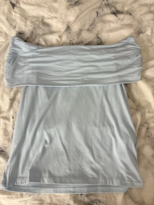 Ljusblå offshoulder tubtopp Amisu XL - Säljer en ljusblå offshoulder tubtopp från Amisu i storlek XL. Toppen är axelbandslös och har en bred, vikt kant upptill som ger en snygg och trendig look. Tillverkad i mjukt och stretchigt material som sitter skönt mot kroppen.
