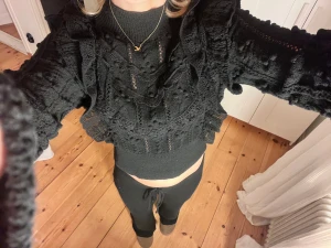 Svart tröja med volang och spets från Zara  - Säljer en svart volang tröja med långärmad design, croppad passform och snygga volangdetaljer. Blusen har spetsmönster och ribbad kant nedtill. Köpt från Zara, slutsåld på hemsidan🥰