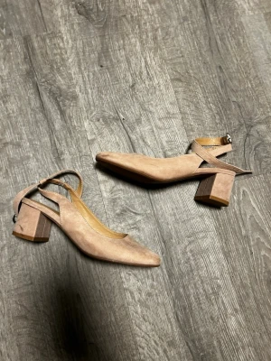 Rosa klackar med blockklack från anna field - Klackar rosa mocka med bred blockklack och rundad tå. Skorna har en rem runt ankeln med spänne. Syns på dem att dem är lite använda vilket jag tagit kort på.