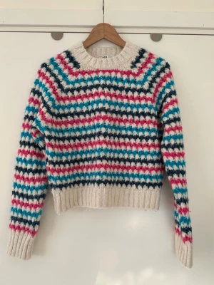 Färgglad stickad tröja från Zara - Gullig stickad tröja från Zara i storlek S med ett färgglatt randigt mönster i rosa, vitt, blått och marinblått. Tröjan har en rund halsringning och ribbade muddar. Varm och supermjuk.   Hämtas i Stockholm eller skickas mot porto. 