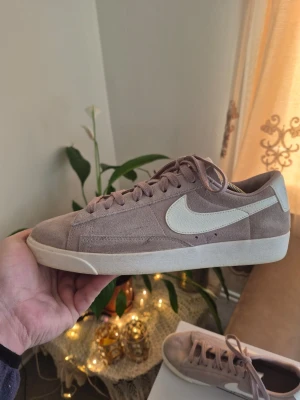Nike suede Blazer Low i ljus rosa mocka Eur 41 - Snygga Nike Blazer Low sneakers i ljus rosa mocka med vit sula och vit swoosh på sidan. Klassisk låg modell med snörning och retrovibbar. Perfekta för dig som gillar stilrena och tidlösa sneakers med en twist.