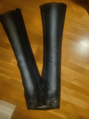 Mörkblå bootcut jeans från Weekday  - Säljer ett par mörkblå bootcut jeans från weekday med snygga slitningar längs benen och klassisk femficksdesign. Jeansen har en tydlig logga bak på linningen och är tillverkade i stretchigt denimtyg för skön passform.