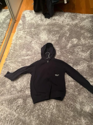 Svart hoodie från Replay - Snygg svart hoodie från Replay med dragkedja framtill och liten vit logga på bröstet där det står 'Replay Denim Goods'. Klassisk passform med huva och långa ärmar. Perfekt till jeans eller joggers för en avslappnad look. Skick 8/10. Vid eventuella frågor kom dm! 🤝
