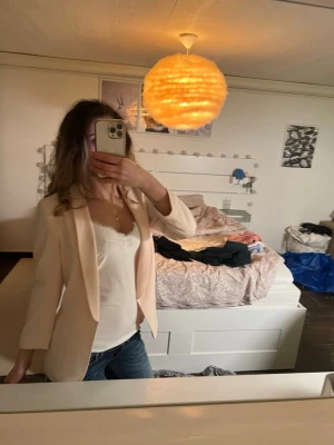 Ljusbeige kavaj - Snygg ljusbeige kavaj med rak passform och klassisk krage. Kavajen har långa ärmar och är tillverkad i ett tunt, mjukt tyg som ger en stilren look. Perfekt att matcha med jeans eller kjol för en trendig outfit.