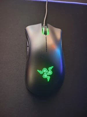 Razer gamingmus  - Säljer en svart Razer gamingmus med ergonomisk form och grymt grepp på sidorna. Musen har en snygg grön LED-logga och upplyst scrollhjul. Perfekt för gaming med extra sidoknappar och sladdanslutning. Tillverkad i plast med mattsvart finish.