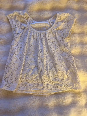 Vit spetsblus med kort ärm - Söt vit blus i spets med blommigt mönster och rund halsringning. Blusen är kortärmad och är av ett luftigt spets material. Från ONLY i storlek XS💗