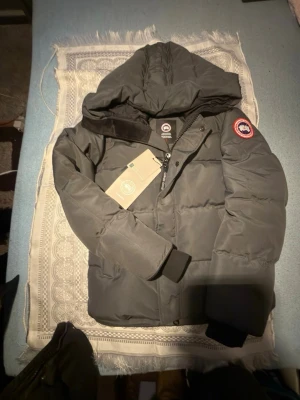 Mörkgrå pufferjacka från Canada Goose (windham) - Säljer en mörkgrå pufferjacka från Canada Goose. Jackan är helt ny och är aldrig använd. Den är skön och varm. 