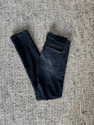 Svarta Slim Nudie Jeans - Ett par läckra Nudie jeans med skön färg. I väldigt bra skick. Passform, slim. Priset är inte spikat, W27 L32