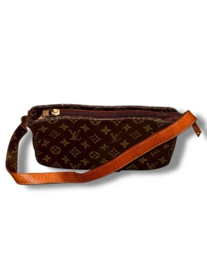Louis Vuitton Monogram axelväska vintage - Snygg vintage axelväska från Louis Vuitton i klassiskt brunt monogrammönster med guldiga detaljer och justerbar axelrem i läder. Väskan har en avlång, rektangulär form och dragkedja upptill. Perfekt för dig som gillar lyxiga accessoarer med ikonisk design. Väskan är köpt på secondhand och vet inte alls värde med mera.