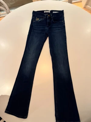 Lois Melose mid high flare jeans 24 L32 - Mid high flare jeans från Lois. Jeansen har en klassisk design med fickor fram och bak, samt en Lois-logga på bakfickan. Använda endast ett par gånger. Ser nya ut, inget slitage.