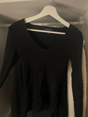 Svart ribbstickad tröja från Amisu - Svart ribbstickad tröja från Amisu med djup v-ringning och långa ärmar. Tröjan har en smal passform och är i jättebra skick och knappt använd. Enkel och stilren design som funkar till det mesta.