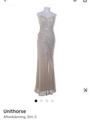 Balklänning - Supersnygg glittrig långklänning från Unithorse i en ljus champagnefärg. Klänningen är axelbandslös med omlott-detalj framtill och har en slits som ger extra edge. Perfekt för dig som vill sticka ut på bal eller fest.
