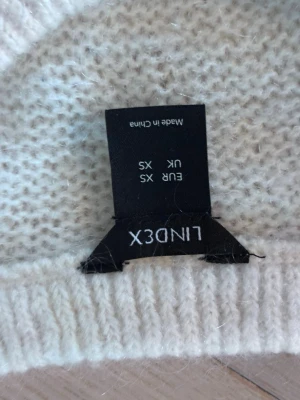 Vit mohair tröja från Lindex XS - Mysig vit stickad tröja från Lindex i storlek XS. Tröjan har en enkel, klassisk design med rund halsringning och ribbstickade muddar. Perfekt för lager på lager och passar till det mesta i garderoben.