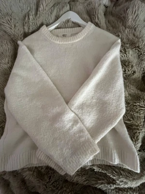 Vit stickad tröja från Gina tricot - Mysig vit stickad tröja från gina med rund halsringning och ribbade muddar vid ärmslut och nederkant. Tröjan har en enkel och clean design som passar perfekt till alla outfits. Materialet känns mjukt och skönt mot huden.