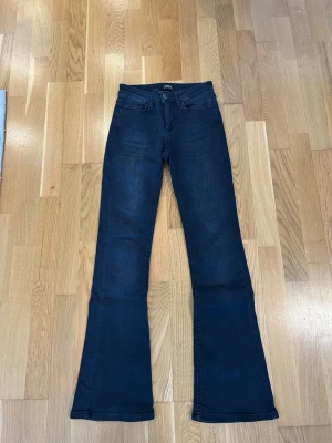 Mörkblå bootcut jeans från ONLY - Snygga mörkblå bootcut jeans från ONLY i midwaist. Jeansen har utsvängda ben och är tillverkade i stretchigt denimtyg som sitter bekvämt. Perfekta för en trendig och avslappnad stil. Storlek XS/30