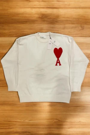 AMI Paris stickad tröja | Storlek S  - Ami Paris tröja i vit med röd logga  Storlek: S  Långärmad tröja med stilig logga på bröstet Perfekt för vardagligt bruk men även för lite lyx! Skickas inom 24h!