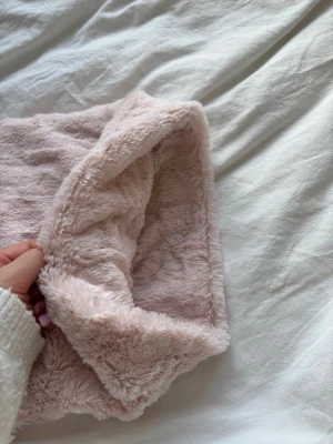 Ljusrosa fluffig tubhalsduk - Supermjuk och fluffig ljusrosa tubhalsduk i fuskpäls. Perfekt för att hålla värmen under kyliga dagar. Halsduken är fyrkantig i formen och känns riktigt gosig mot huden. Enkel att dra över huvudet och passar till många olika stilar.