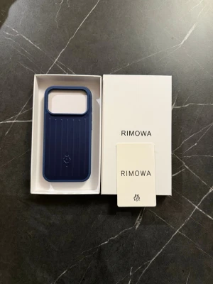 Rimowa iphone 17 pro - Snyggt blått mobilskal från Rimowa med klassisk räfflad design och diskret logga på baksidan. Skalet är gjort i tåligt material och har en modern, stilren look som passar perfekt till din mobil. Levereras i originalförpackning.