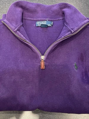  Polo Ralph Lauren quarter zip  - Snygg lila tröja från Polo Ralph Lauren med dragkedja och ståkrage. Tröjan har broderad logga på bröstet och är tillverkad i mjukt bomullsmaterial. Perfekt för lager-på-lager och en chill stil.