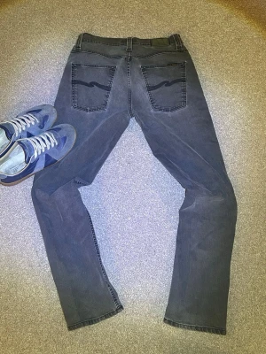 Gråa Nudie jeans - Ruskigt snygga jeans ifrån Nudie. Jeansen är i bra skick och lite meningen med Nudie jeans är att man själv gör dom snygga genom att ha på sig dom och därför är det rätt så speciella jeans. Tveka inte vid frågor!