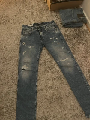 Replay anbass - Säljer ett par Replay anbass jeans med slitningar framtill. Jeansen har klassisk femficksmodell och en läderpatch bak i midjan. Perfekta för en avslappnad och trendig look. Nypris: 1700 Vårt pris: 599