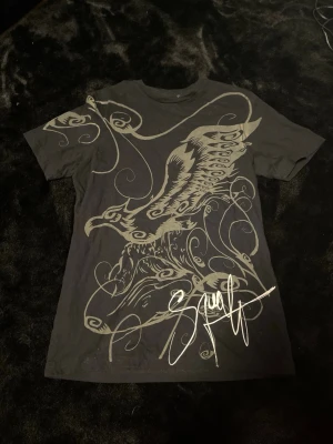 Svart t-shirt med örntryck - Cool svart t-shirt med stort grafiskt tryck av en örn och snirkliga mönster på framsidan