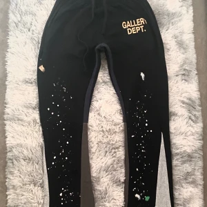  Gallery Dept.  - Svarta mjukisbyxor från Gallery Dept. med gult tryck på höften och unika färgstänk i vitt och grönt. Byxorna har snörning i midjan och är tillverkade i 100% bomull. Perfekt för dig som gillar streetwear. Kan även tillägga att det passar För de som har storlek M. Pris går även att diskutera 