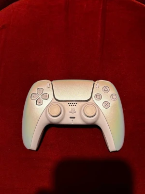  PlayStation 5 DualSense handkontroll - Säljer en chroma pearl PlayStation 5 DualSense handkontroll från Sony. Kontrollern har en skimrande pärlemorfärg, klassisk ergonomisk form och tydliga PlayStation-knappar. Tillverkad i plast med två analoga spakar, styrkors och triggers. Perfekt för gaming på PS5.