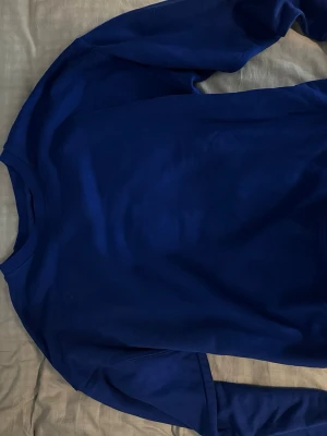 Blå sweatshirt från Lindex - En stilren blå sweatshirt från Lindex med rund halsringning och långa ärmar. Tröjan är i mjukt material och passar perfekt till en avslappnad look. Enkel design utan tryck eller mönster.