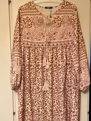 *NY*Längre klänning i stl M fr Sheilay - Ny oanvänd, bara provad.   Tunn luftig oversizemodell i M, sitter nog bäst på en 40/42.  Ljusbeigerosa med leomönster i brunt.  Jag är 1,67 och den går ner till mina anklar. Perfekt för dig som gillar boho-vibbar och djurmönster.